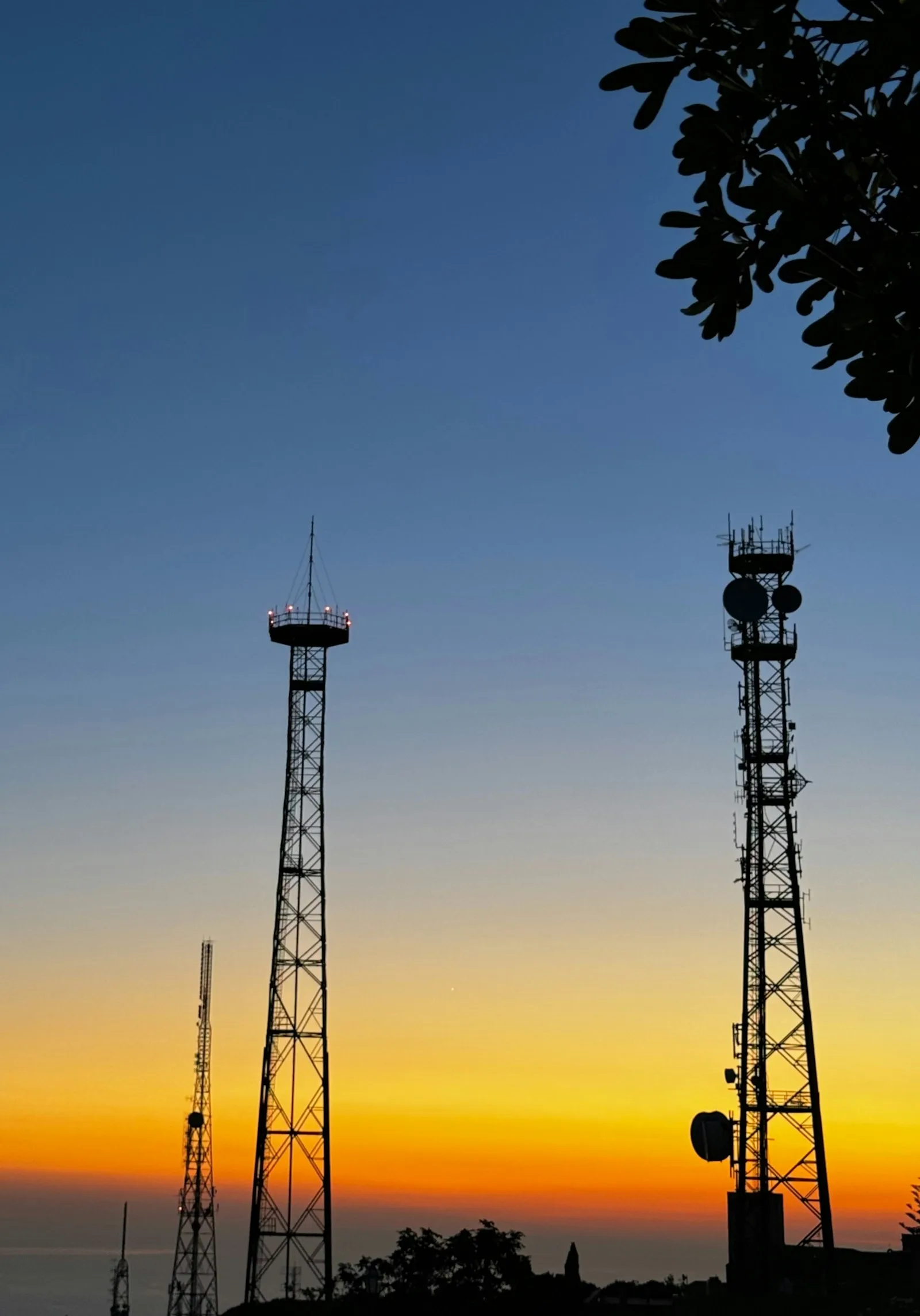 Communications towers silhouetted against the evening sky