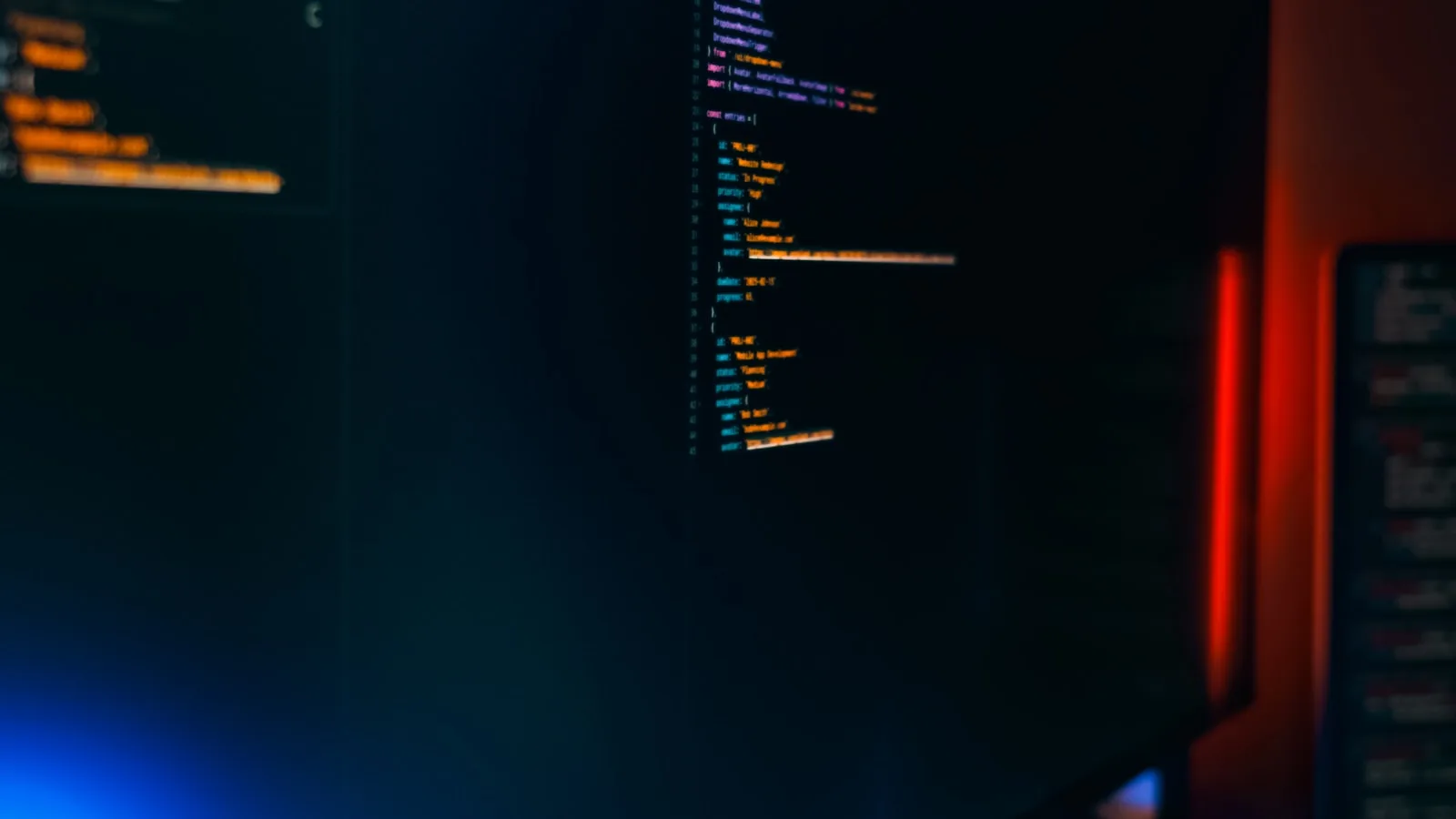 Software code glowing across monitors in a dark workspace